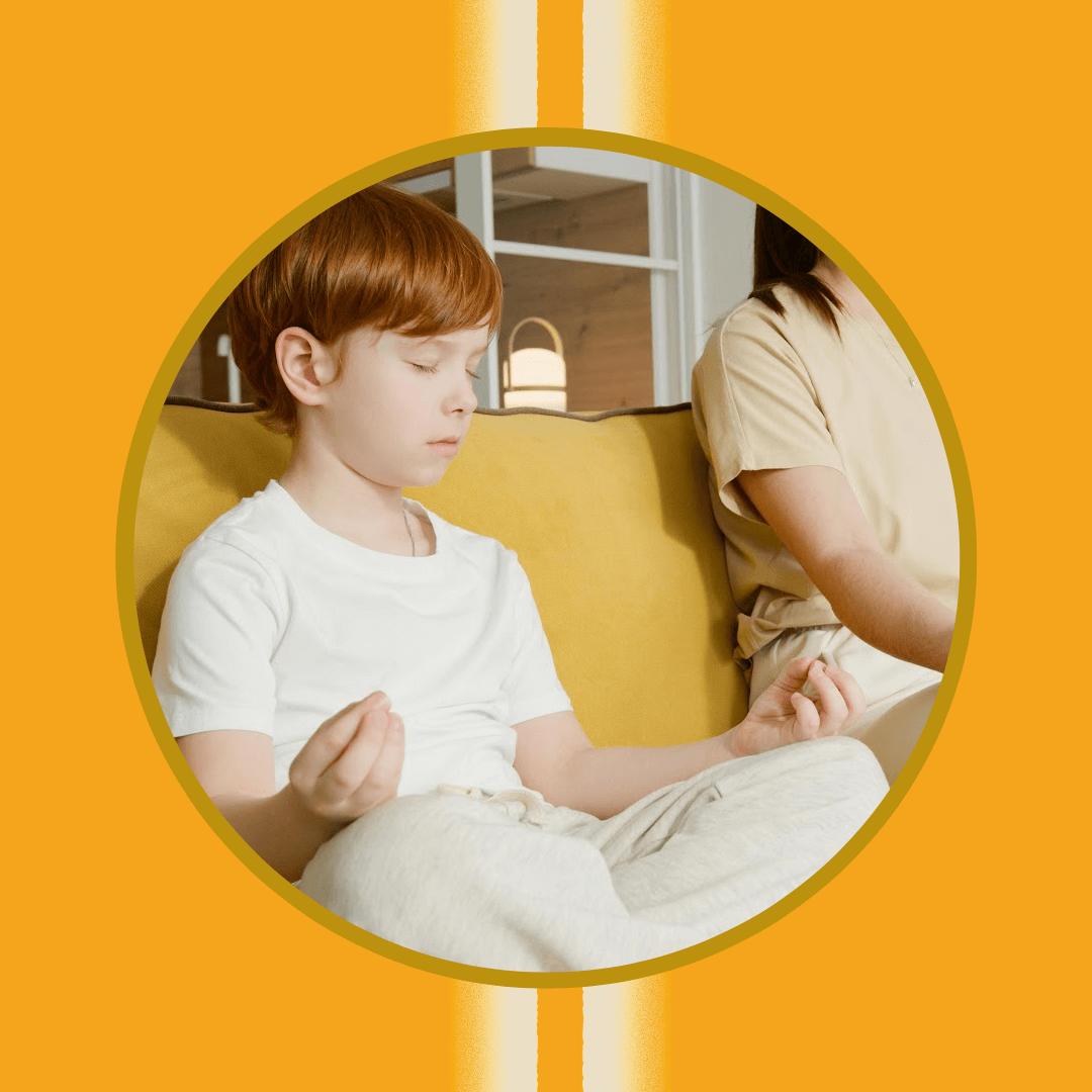A child with red hair sits cross-legged on a yellow couch, eyes closed, with hands in a meditation pose. An adult sits beside the child, partially out of frame, against an orange background.